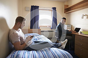 Male Students Working In Bedroom Of Campus Accommodation