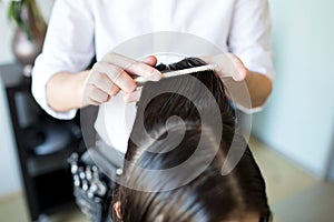 Male stylist hands combing wet hair at salon