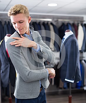 Male in suit trying jacket in the clothes store