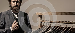 Male suits hanging in a row. Men clothing, boutiques. Tailor, tailoring. Stylish men's suit. Man suit, tailor in his