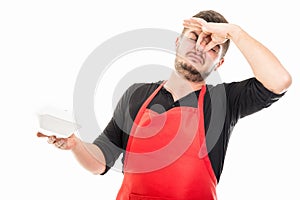 Male supermarket employer gesturing bad smelling lunch box