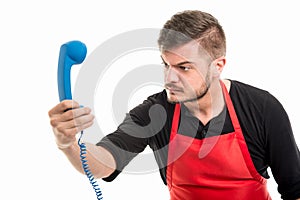 Male supermarket employer looking angry at blue phone receiver