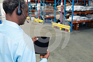 Male supervisor with headset using digital tablet in warehouse