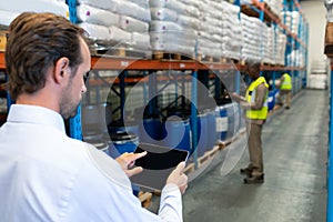 Male supervisor working on digital tablet in warehouse