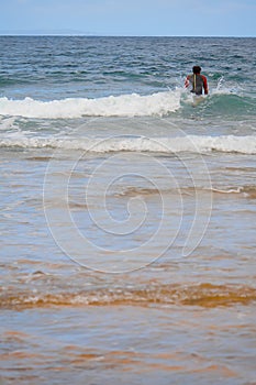 Male surfer in a black swim suit in the ocean with blue surfboard. Warm day, Beautiful cloudy sky, Nature scene. Atlantic ocean,