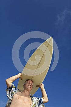 Male surfer carrying surfboard on head