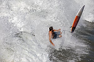 Male surfer falls off surfboard