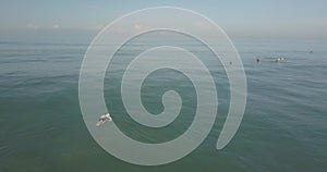 Male surfer paddling with a longboard in the wavy sea