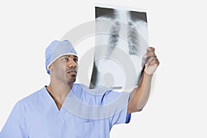 Male surgeon analyzing x-ray report over gray background