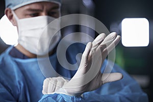 Male surgeon putting on latex gloves in preparation