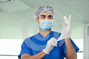 male surgeon putting on latex gloves in preparation