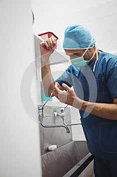 Male surgeon washing hands prior to operation using correct technique for cleanliness