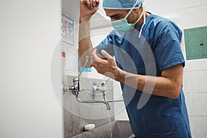 Male surgeon washing hands prior to operation using correct technique for cleanliness