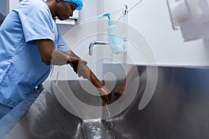 Male surgeon washing hands in sink at hospital