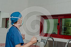 Male surgeon is washing his hands in a hospital sink