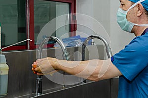 Male surgeon is washing his hands in a hospital sink