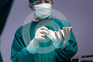 Male surgeon wearing medical protective gloves and surgical mask in operation theater at hospital, Medical team performing