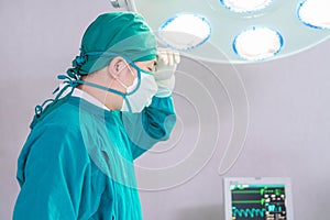 Male surgeon wearing surgical mask in operation theater at hospital, doctor in operating room