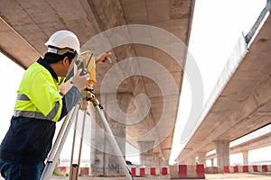 A male surveyor engineers worker making measuring under the expressway with theodolite on road works. Survey engineer at road