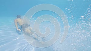 Male swimmer dive on blue water in swimming pool at start slow motion. Young man jumping in transparent water on