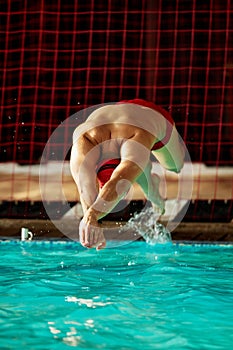 A male swimmer dives into the pool with his head into the water, the start of the swim in the pool.