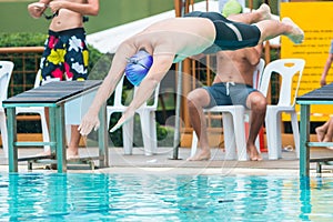 Male swimmer juming of the start platform into the pool