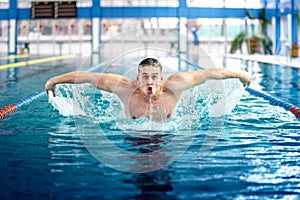 Male swimmer, performing the butterfly stroke technique at indoor pool