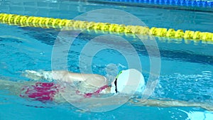 Male swimmer starting block and start swims in pool. Professional athlete training: dive and splashes water surface