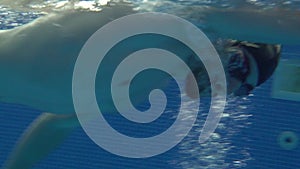 Male swimmer swimming crawl stroke in swimming pool underwater view