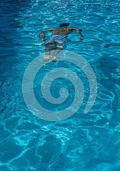 Male swimmer underwater viewed from above a pool