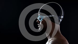 Male swimmer wearing goggles and preparing to jump into swimming pool, close-up