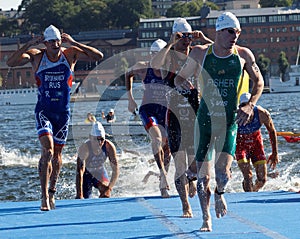 Male swimmers climbing up from the water