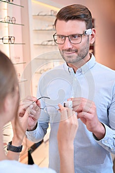 Male talking with a female shop assistant about optical fashion in the store