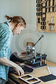 Male tanner working with handpress device machine cutting pattern on stuff material leather workshop