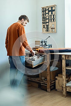 Male tanner working with handpress device machine cutting pattern on stuff material leather workshop