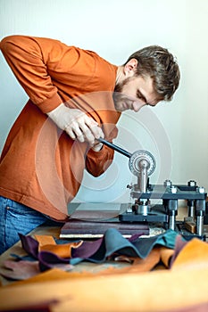 Male tanner working with handpress device machine cutting pattern on stuff material leather workshop