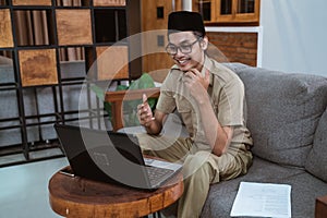 male teacher in civil servant uniform with hand gestures during online meeting using a laptop computer