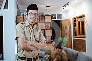 male teacher in civil servant uniform smiling with a crossed hand while working with the team from home