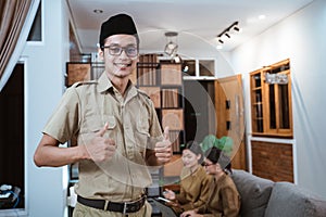 male teacher in civil servant uniform smiling with a thumbs up while working with the team from home