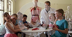 Male teacher and group of kids smiling in human anatomy class