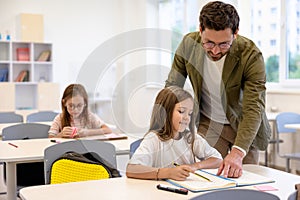 Male teacher helping pupils while writing the test