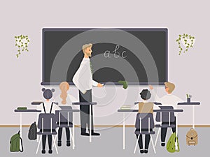Male teacher of Philology explaining english letters to elementary school pupils or children near chalkboard. Man teaching photo
