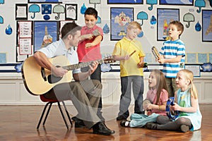 Male Teacher Playing Guitar With Pupils photo