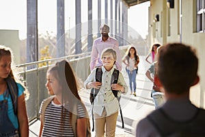 Male teacher and pupils walk on elementary school campus