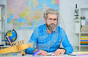 Male teacher takes exam in university. Bearded student in glasses and denim shirt sitting at desk in classroom. Test of