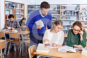 Male teacher working with young female students in university library