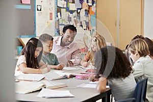 Male teacher works with elementary school kids at their desk