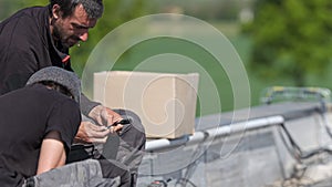 Male team engineers installing stand-alone solar photovoltaic panel system. Electricians mounting blue solar module on roof of