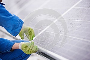 Male technician in blue suit installing photovoltaic blue solar modules with