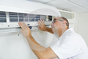 Male technician checking air conditioner at home